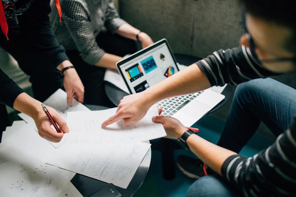 Free Image of Group of People Sitting Around a Laptop Computer 