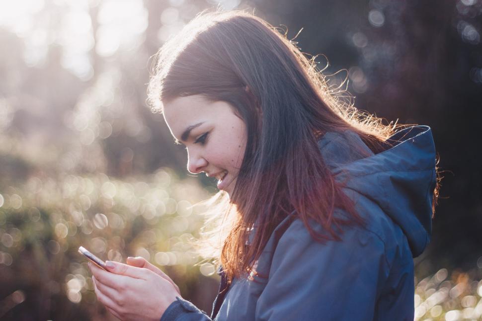 Free Image of Woman in Blue Jacket Looking at Cell Phone 