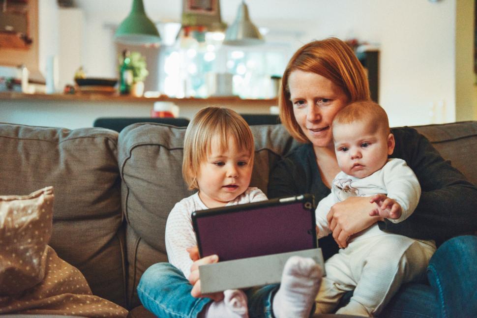 Free Image of A Woman and Two Children Sitting on a Couch 