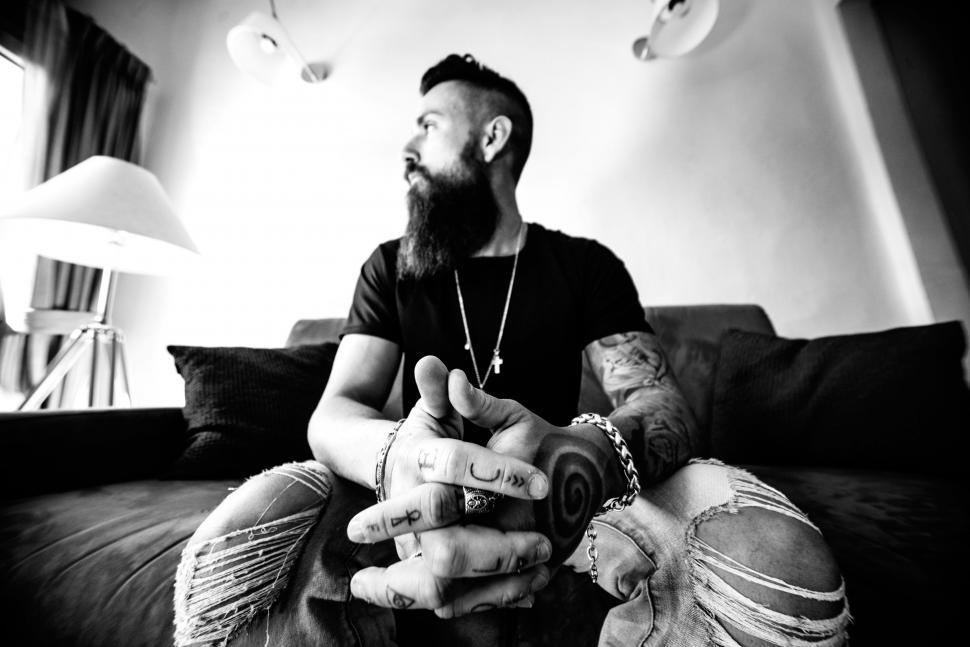 Free Image of Man Sitting on Top of a Couch Next to a Lamp. 