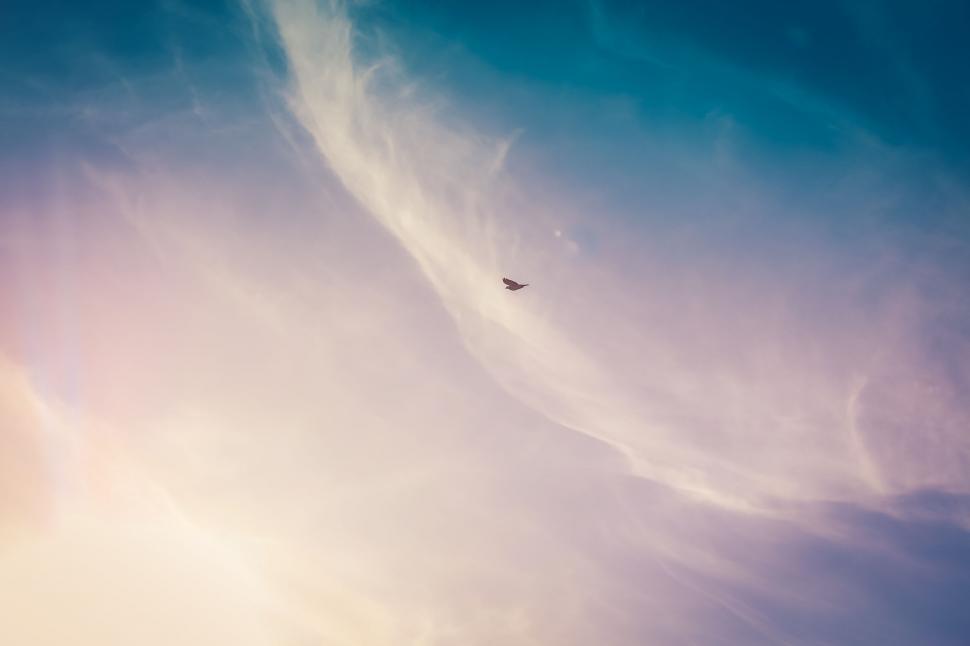 Free Image of A Plane Flying Through a Cloudy Blue Sky 