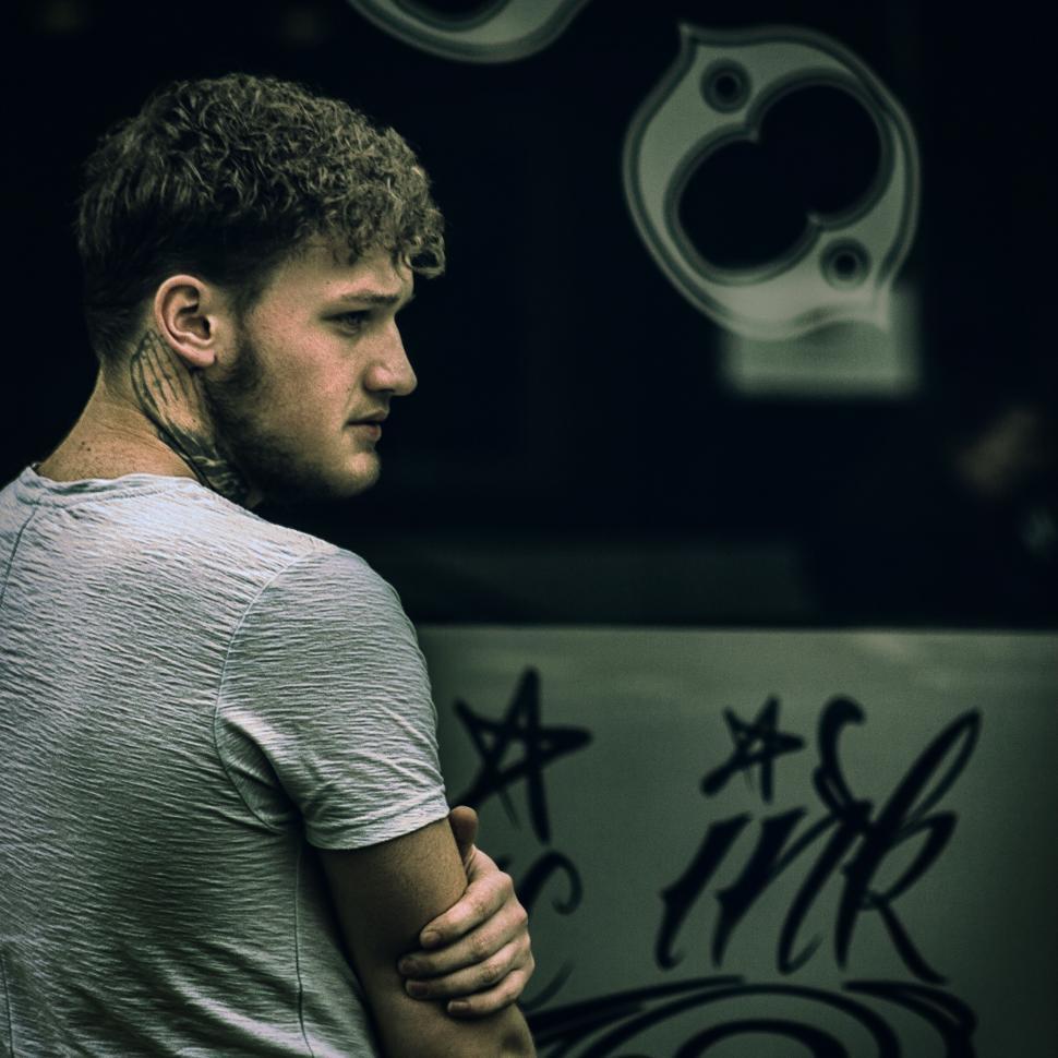 Free Image of Man Standing in Front of Graffiti Covered Wall 