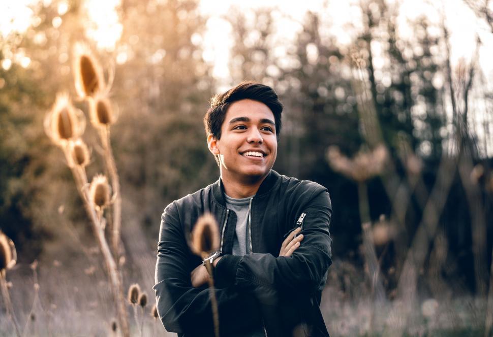 Free Image of Man Standing in Field With Arms Crossed 