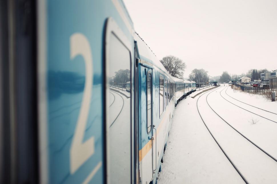 Free Image of Train Traveling Down Snow-Covered Train Tracks 