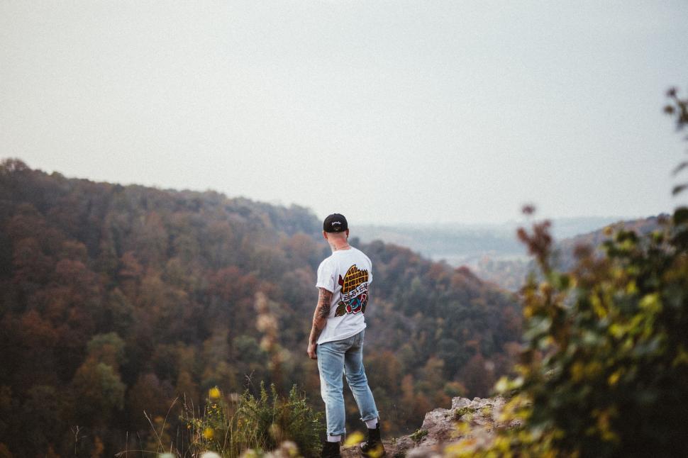 Free Image of Man Standing on Top of Lush Green Hillside 