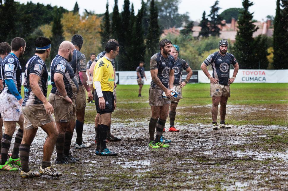 Free Image of Group of Men Standing on Top of Muddy Field 