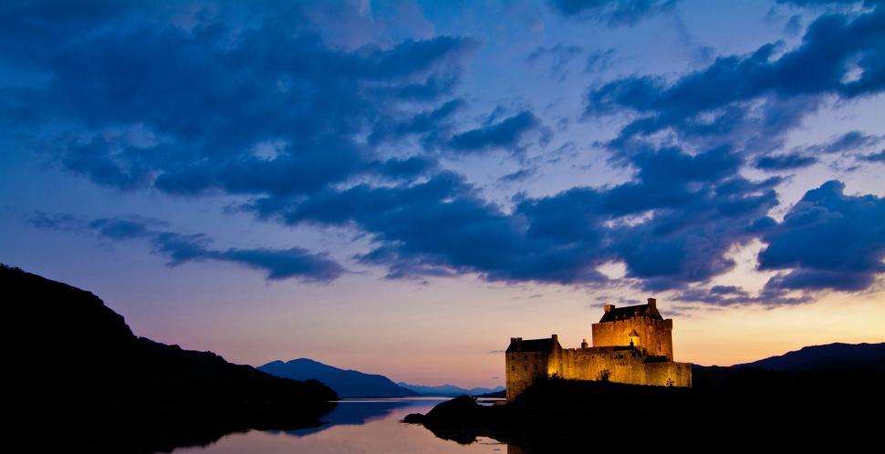Free Image of Castle Overlooking Lake on Cloudy Day 
