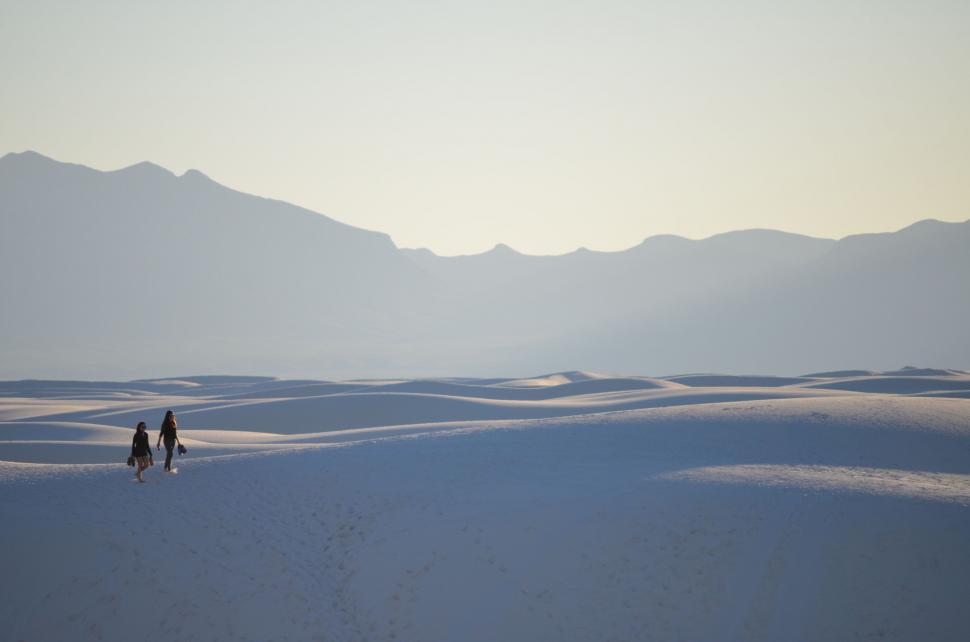 Free Image of Two People Walking Across Snow-Covered Field 