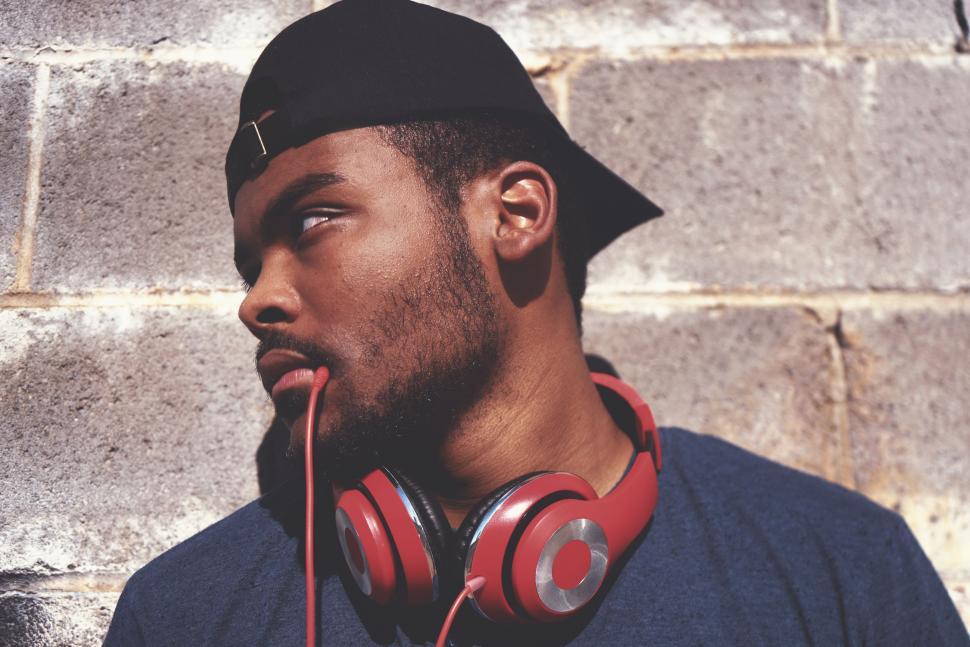 Free Image of Man Listening to Music Standing in Front of Brick Wall 