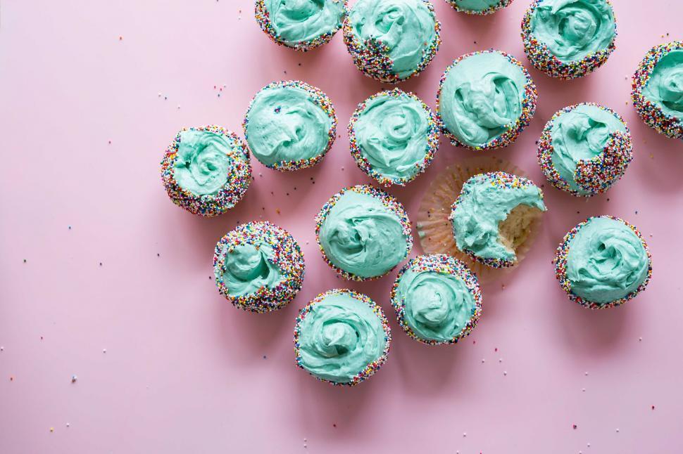 Free Image of Cupcakes With Blue Frosting and Sprinkles on a Pink Background 