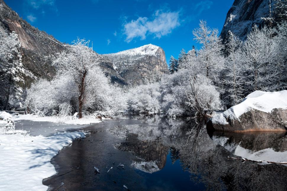 Free Image of Snow-Covered Mountains Surrounding River Under Blue Sky 