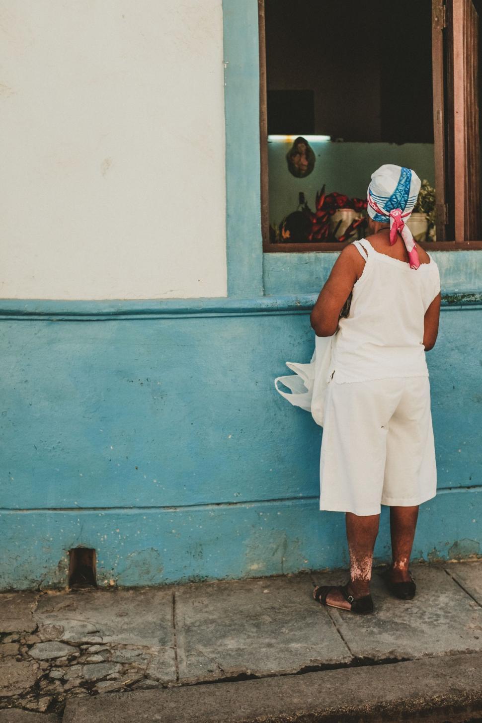 Free Image of Woman in White Dress in Front of Blue Building 
