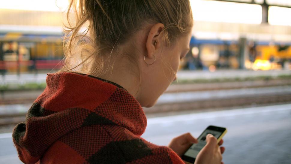 Free Image of Woman Checking Cell Phone at Train Station 