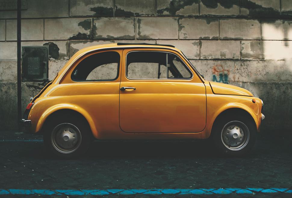 Free Image of Small Yellow Car Parked in Front of Building 