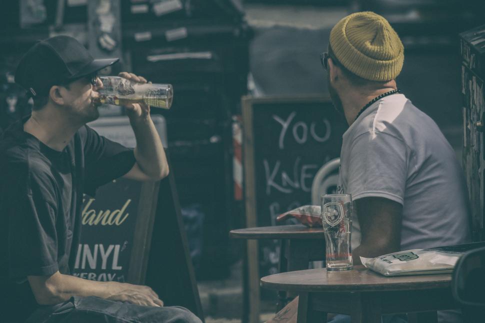 Free Image of Man Sitting at Table Drinking From Bottle 