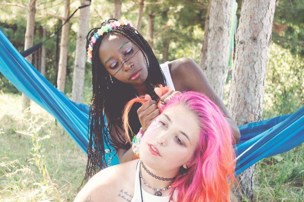 Free Image of Two Women Sitting in a Hammock in the Woods 