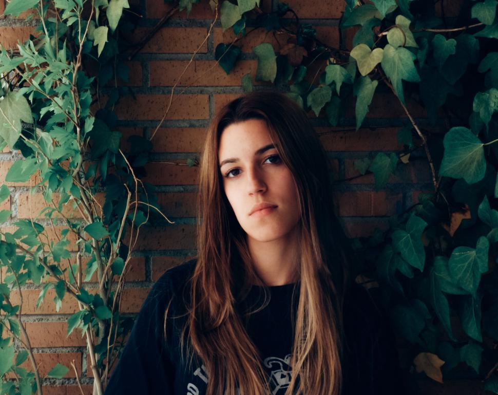 Free Image of Woman Standing in Front of Brick Wall 