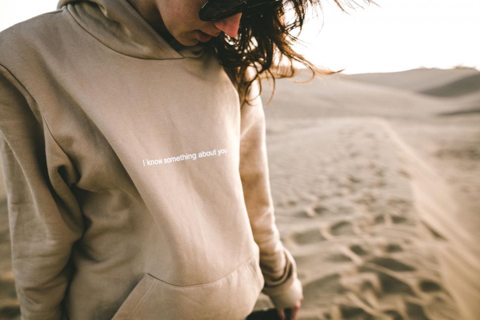 Free Image of Woman Standing in Sand Wearing Hoodie 