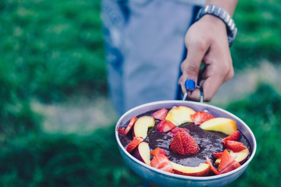 Free Image of Person Holding Pan of Fruit on Stick 