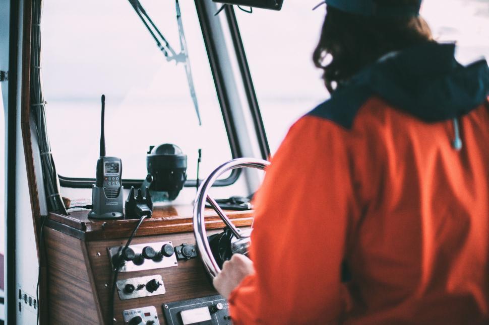 Free Image of Man in Orange Jacket Driving Boat 