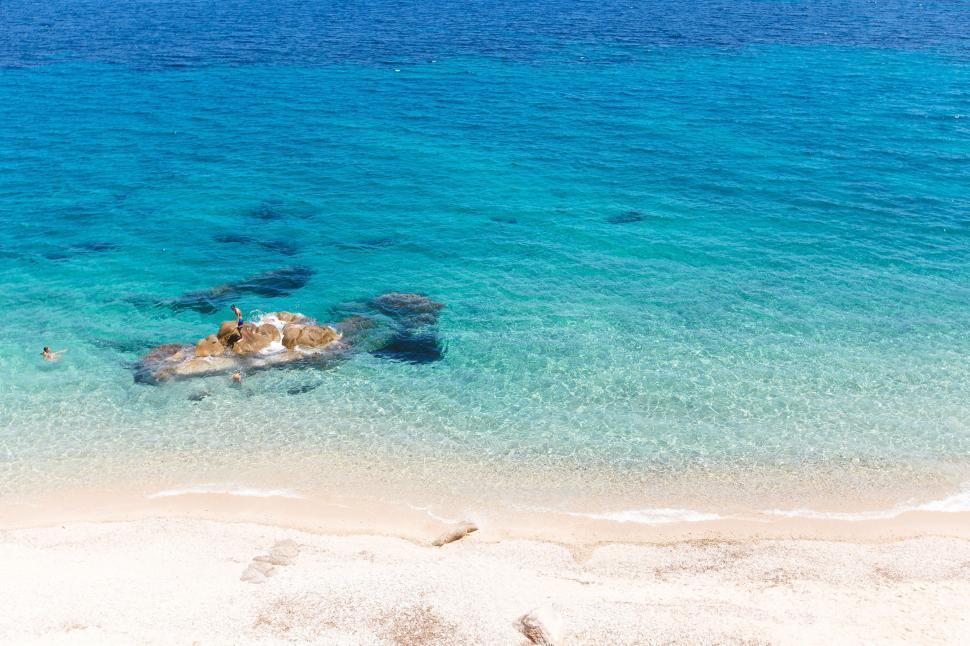 Free Image of Sandy Beach With Clear Blue Water and Rocks 