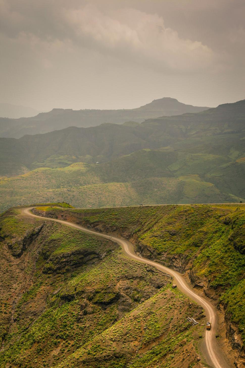 Free Image of Dirt Road Winding Through Lush Green Valley 