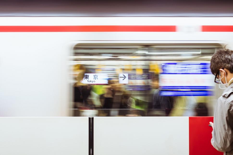 Free Image of Man Wearing Face Mask Standing in Front of a Train 