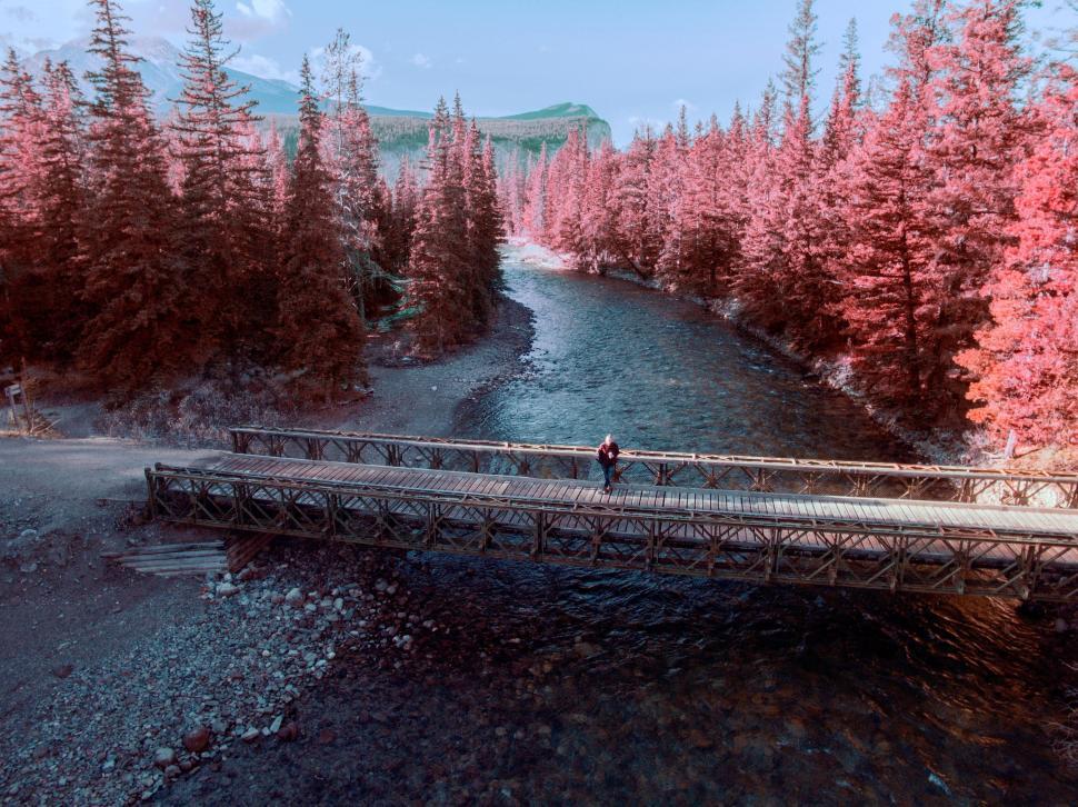 Free Image of Man Walking Across Bridge Over River 