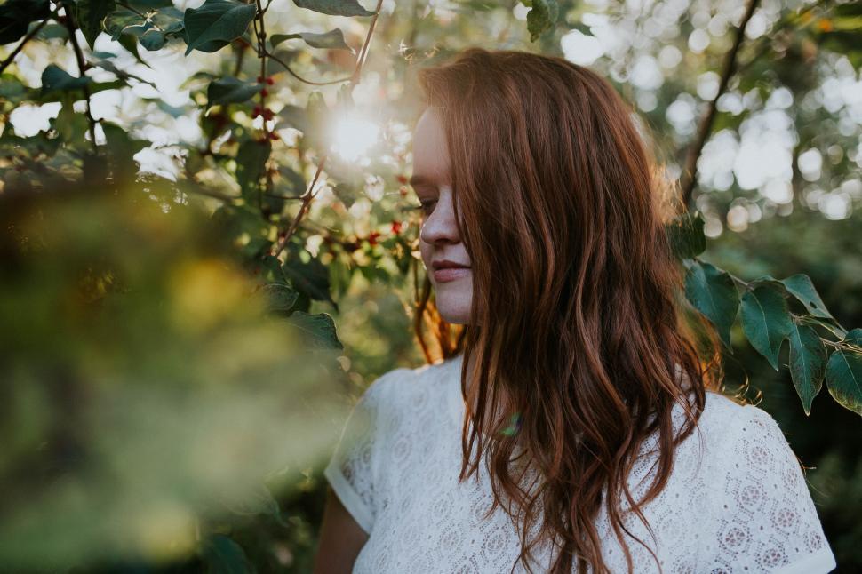 Free Image of Woman With Red Hair Standing in Front of Tree 