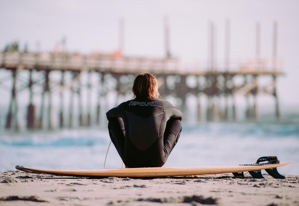 Free Image of Person Sitting on Beach With Surfboard 