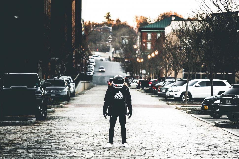 Free Image of Man Riding Skateboard Down Street Next to Parked Cars 