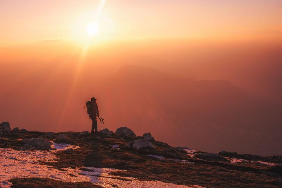Free Image of Person Standing on Top of a Mountain at Sunset 