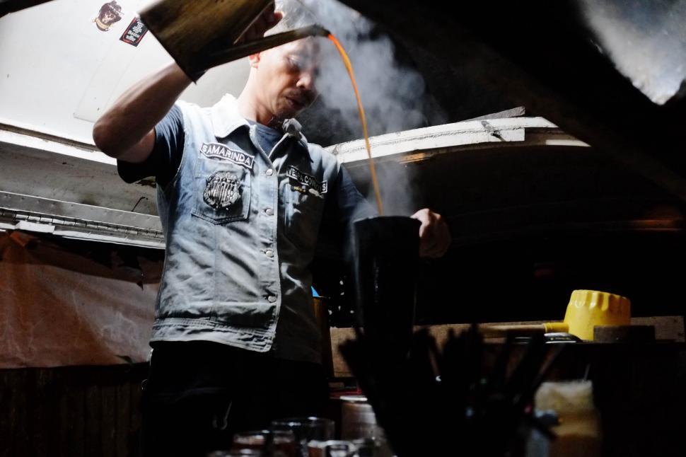Free Image of Man Pouring Liquid Into Pot 