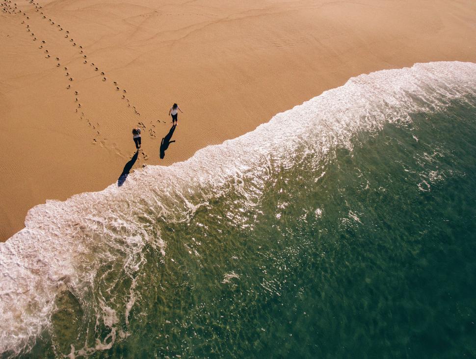 Free Image of Couple Walking Along Beach at Ocean 