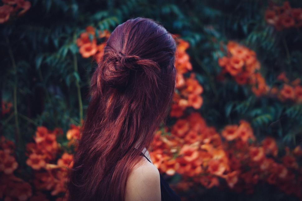 Free Image of Woman Standing in Front of Flowers 