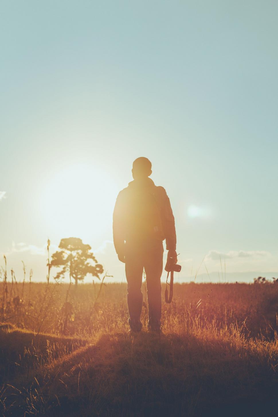 Free Image of Man Standing in Field Holding Skateboard 