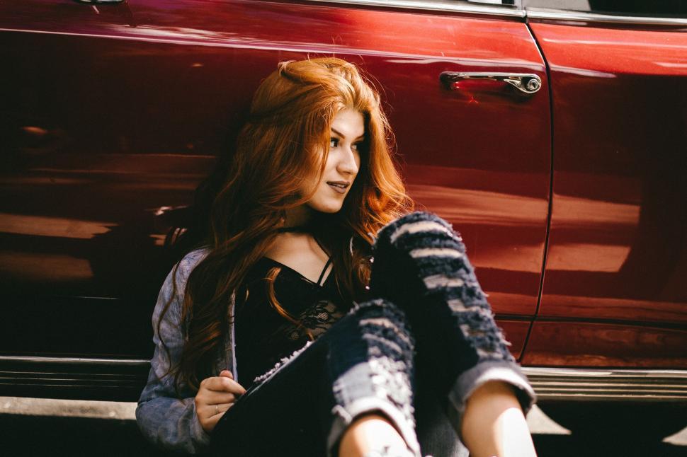 Free Image of Woman Sitting in Front of Red Car 