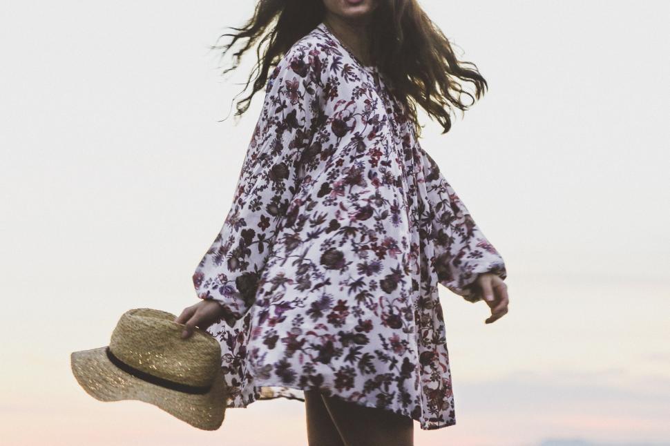 Free Image of Woman in Dress and Hat Walking on Beach 