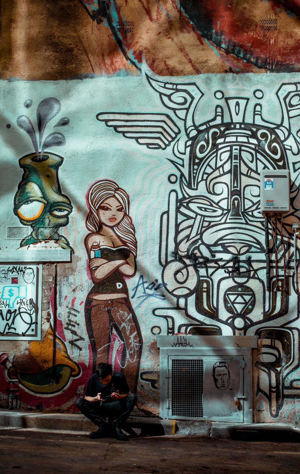 Free Image of Man Riding Skateboard Past Graffiti Covered Wall 