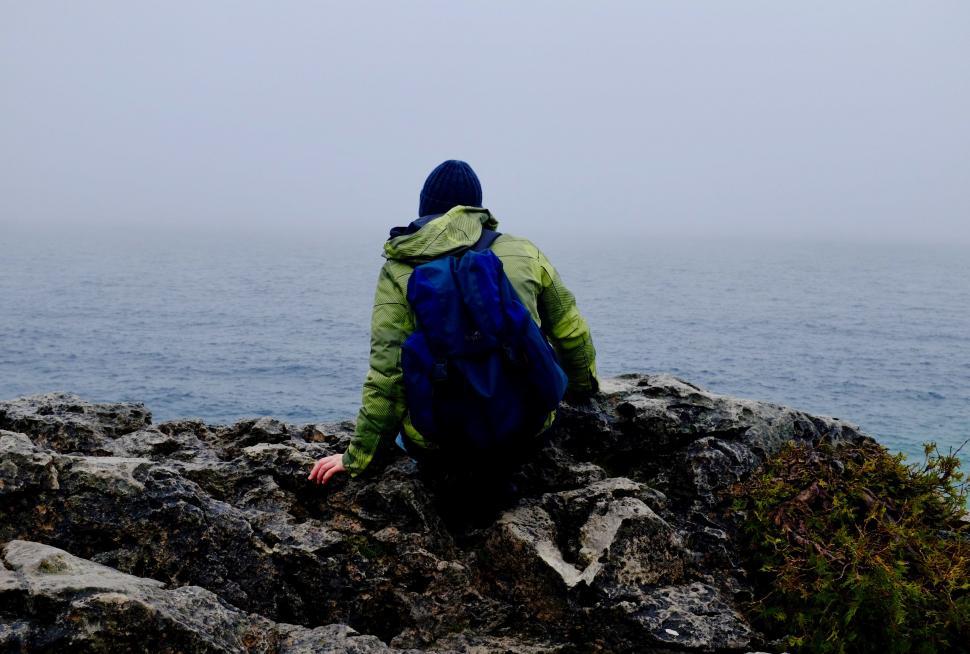 Free Image of Person Sitting on Rock Looking Out at Ocean 
