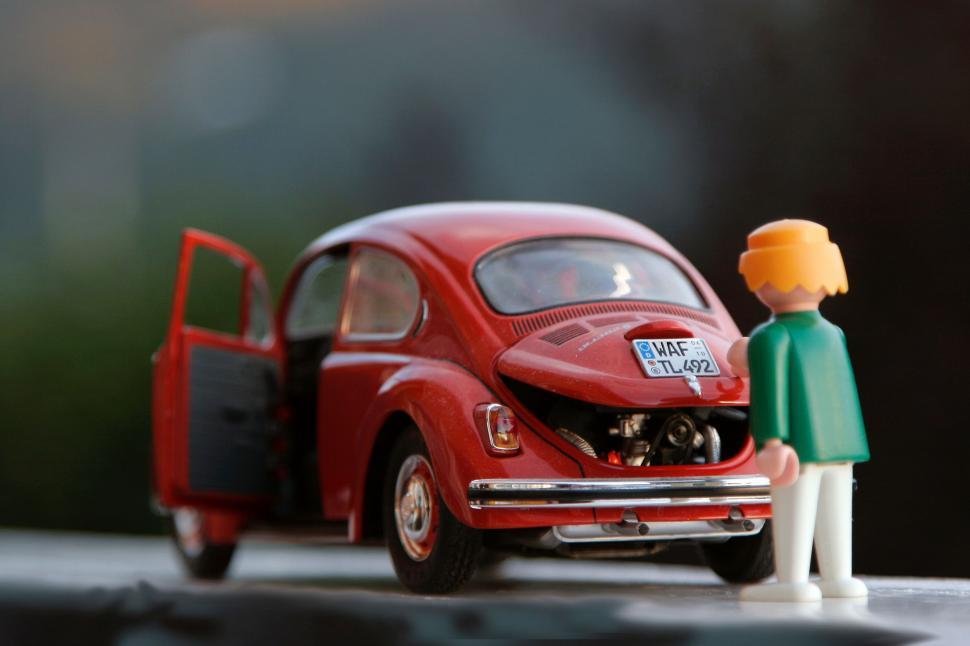 Free Image of Red Toy Car With Man Standing Beside It 