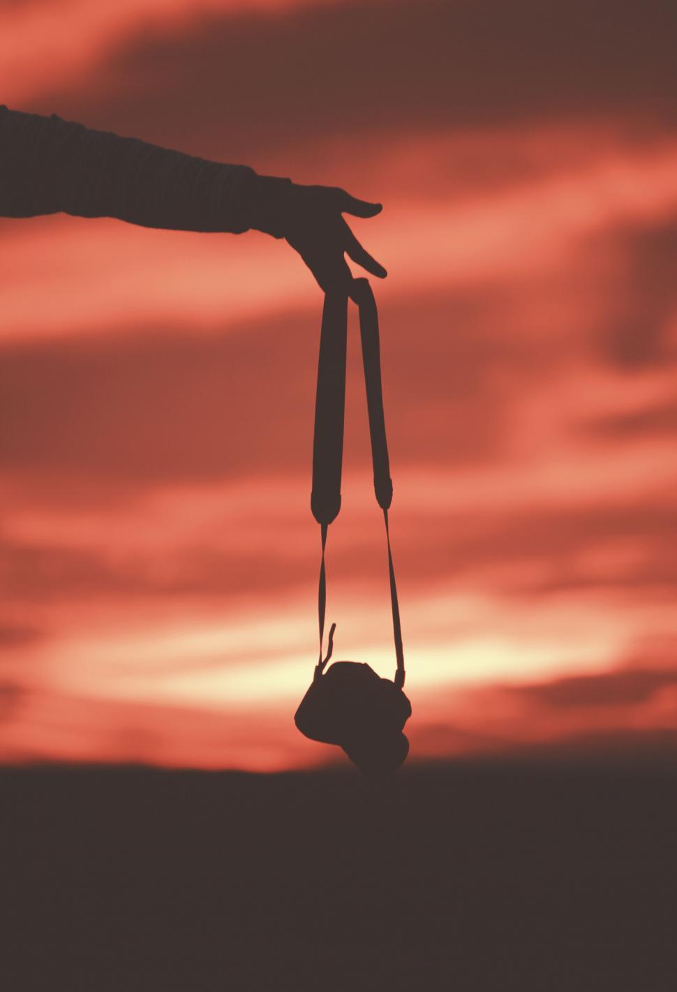 Free Image of Person Holding Camera in Front of Sunset 