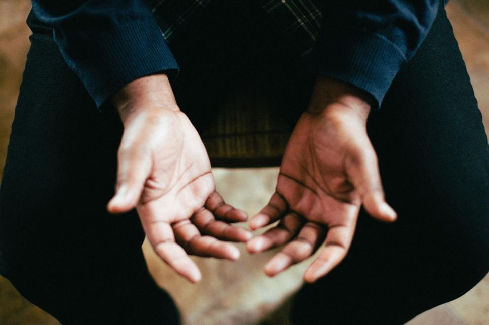 Free Image of Man Sitting on Ground Holding Hands Together 