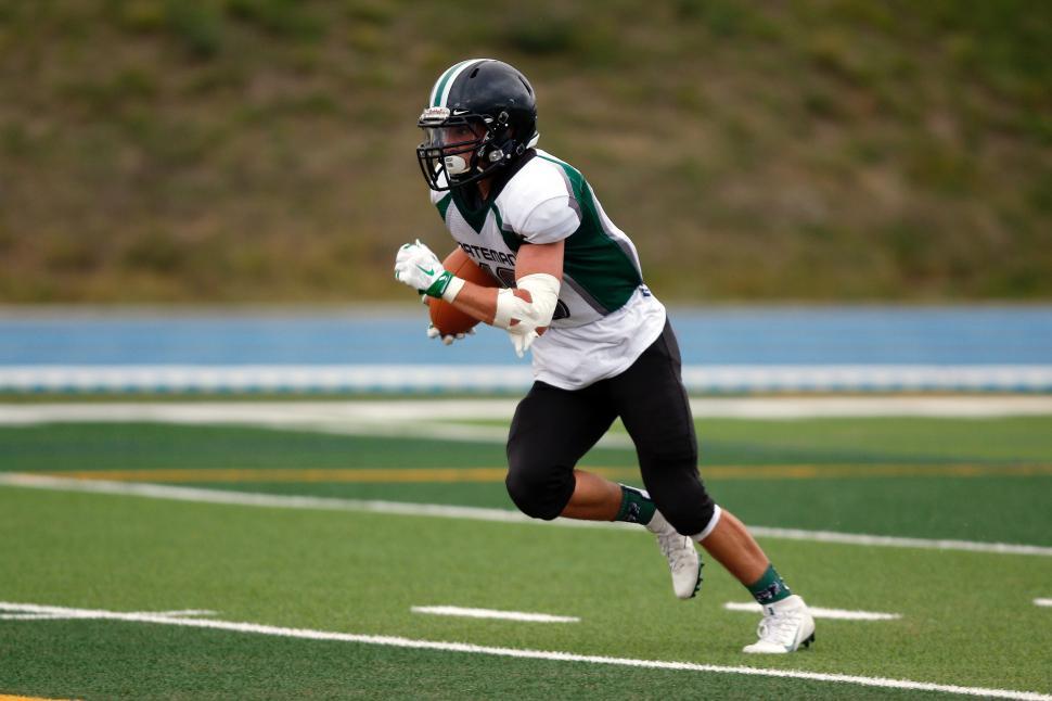 Free Image of Football Player Running With Ball on Field 