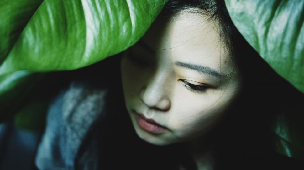 Free Image of Woman Hiding Behind Large Green Leaf 