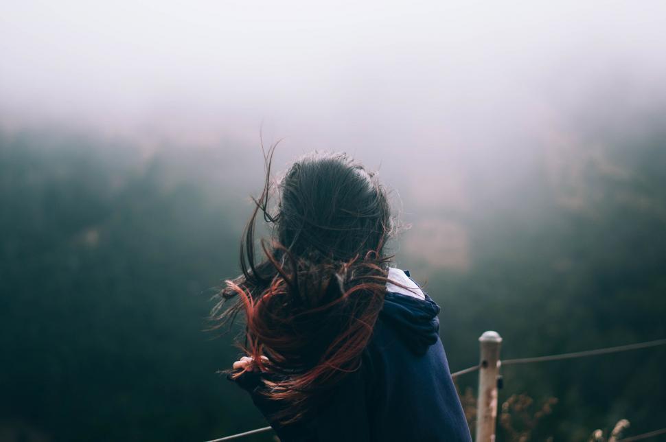 Free Image of Person With Long Hair Standing in Front of Fence 