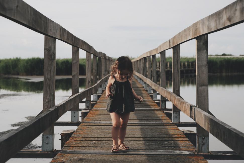 Free Image of Woman Walking Across Wooden Bridge Over Water 