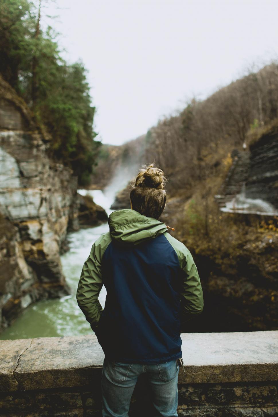 Free Image of Man Standing on Bridge Looking at Waterfall 