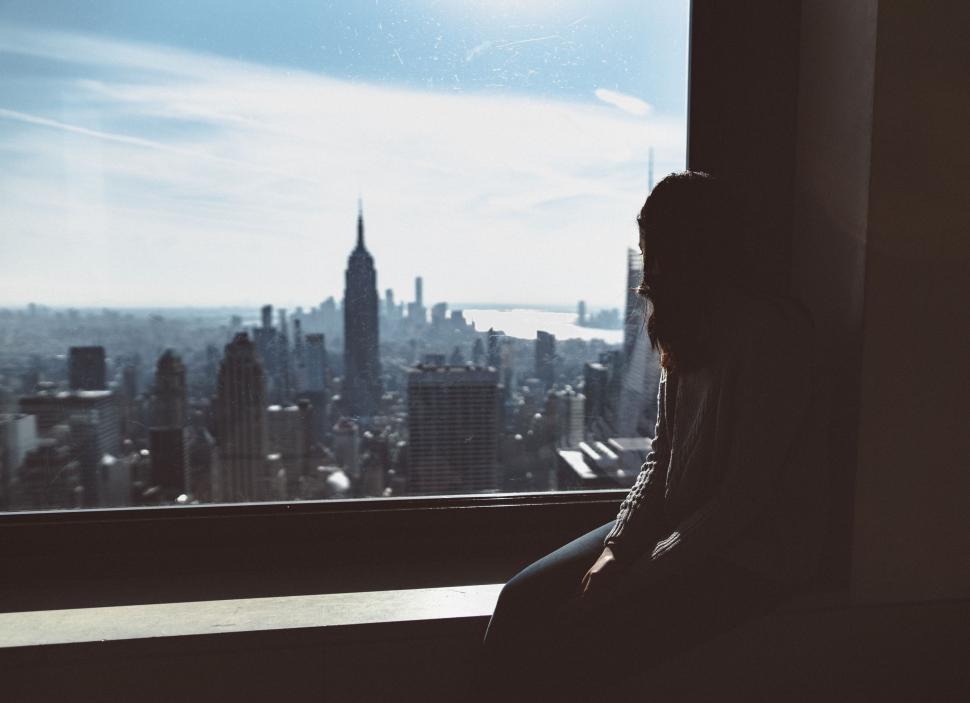 Free Image of Person Looking Out a Window at City 