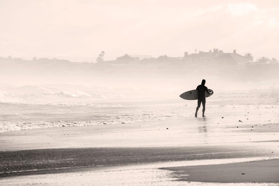 Free Image of Man Holding Surfboard on Sandy Beach 